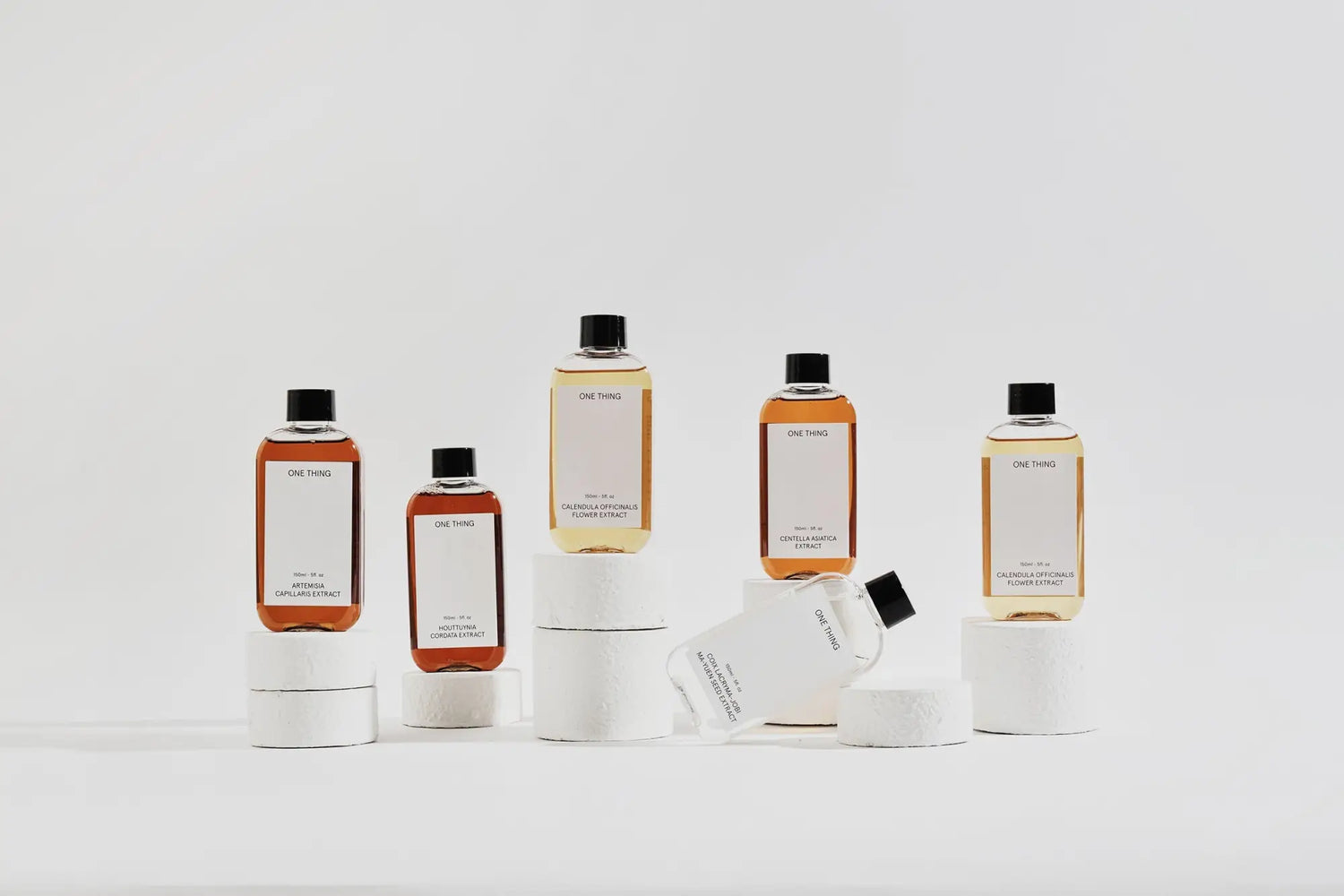 Amber-colored liquid products in clear bottles with black caps from Onething collection